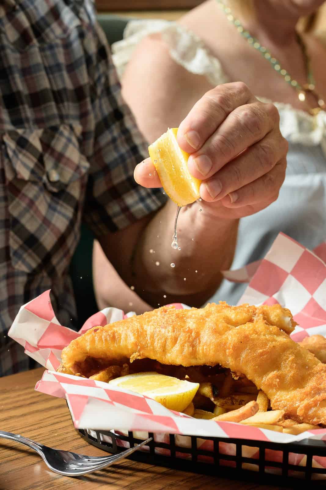 Person squeezing lemon over fried fish at Bill's Bait Shop.